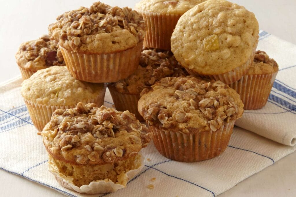 Apple Oat Muffins on a plate with fresh apples and oats in the background.