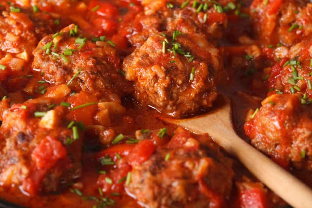 Slow Cooker Italian Meatballs in tomato sauce, garnished with fresh parsley and Parmesan