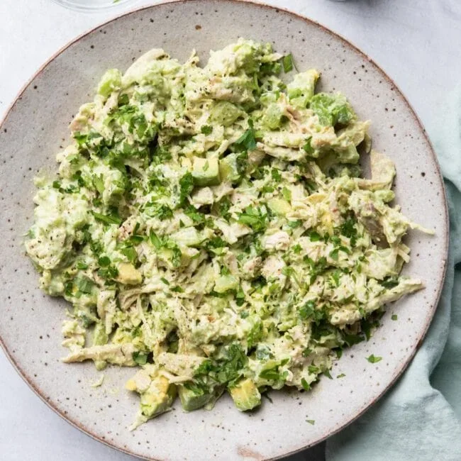 creamy avocado chicken salad with celery and green onions in a white bowl