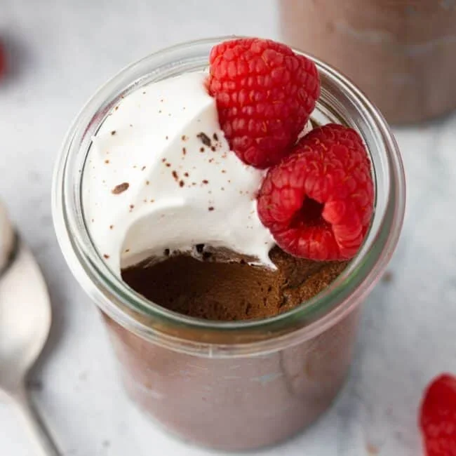 creamy chocolate avocado mousse in glass bowl with whisk