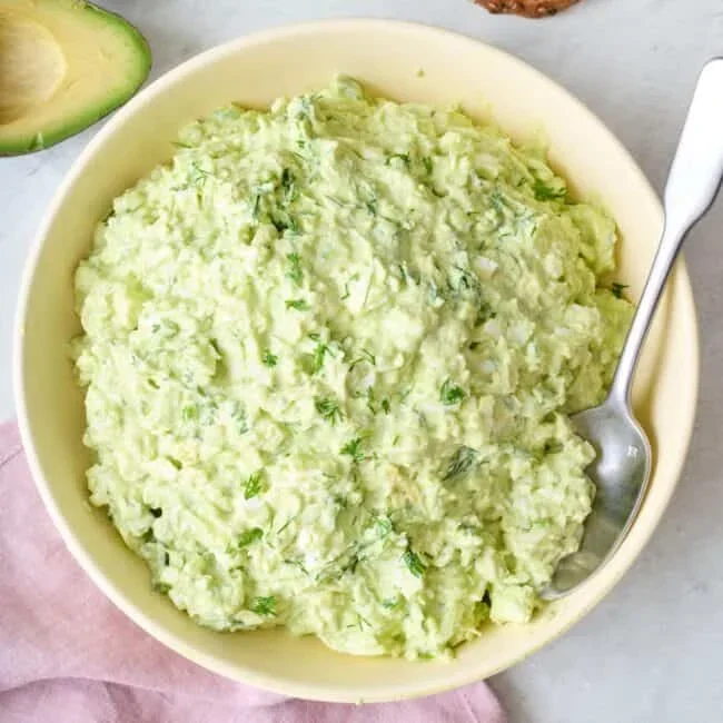 overhead shot of various avocado dishes including toast, salad, and dip