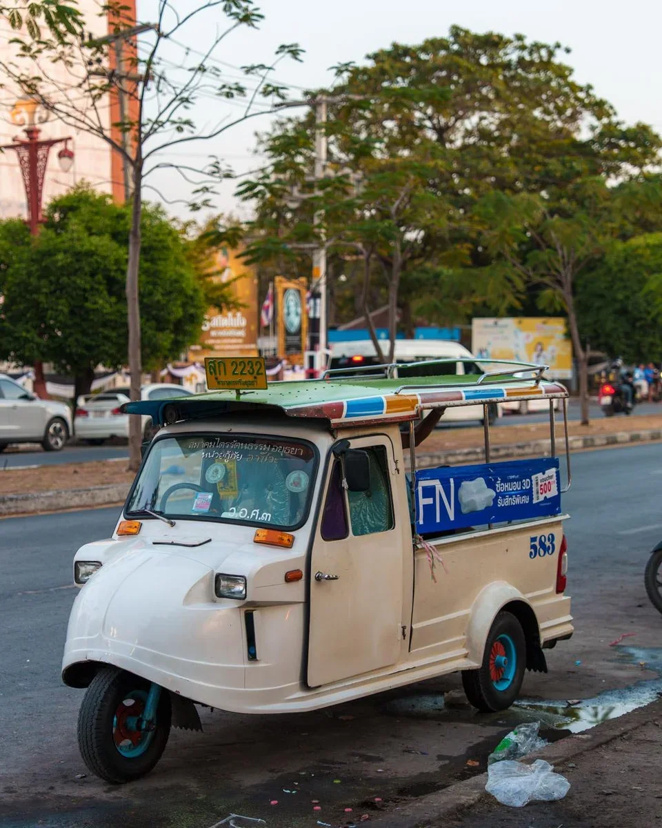 Red tuk-tuk waiting near ancient temple ruins in Ayutthaya historical park