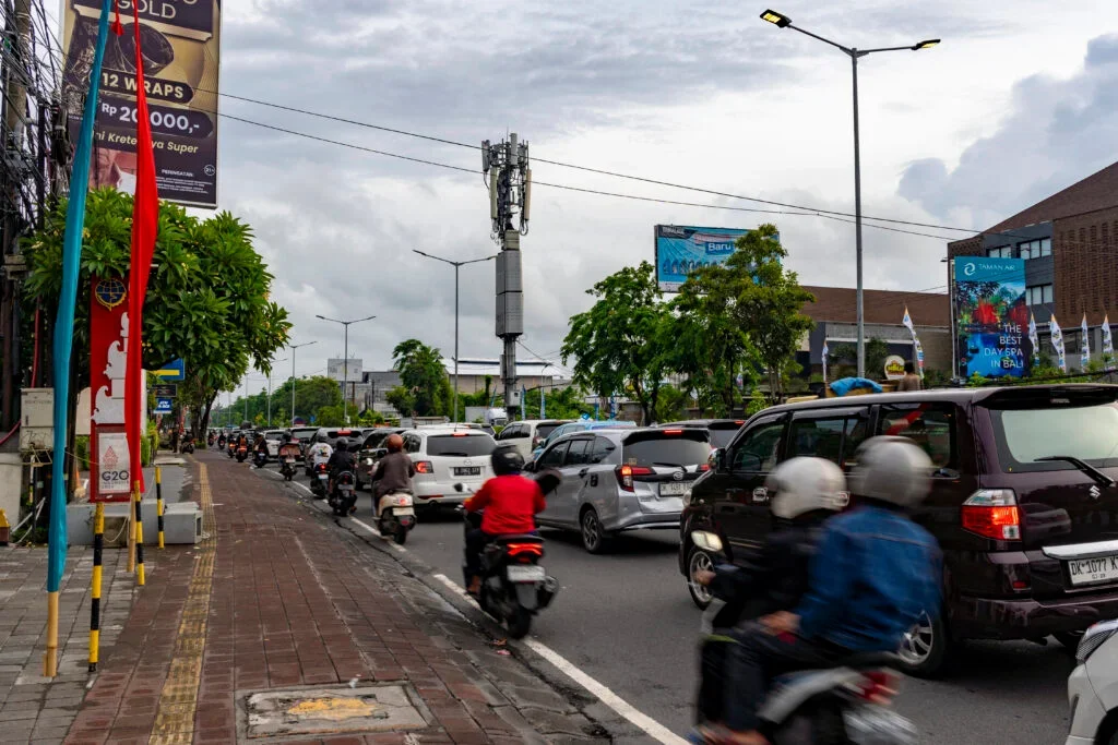 Typical narrow Bali road with motorbikes and cars navigating tight space