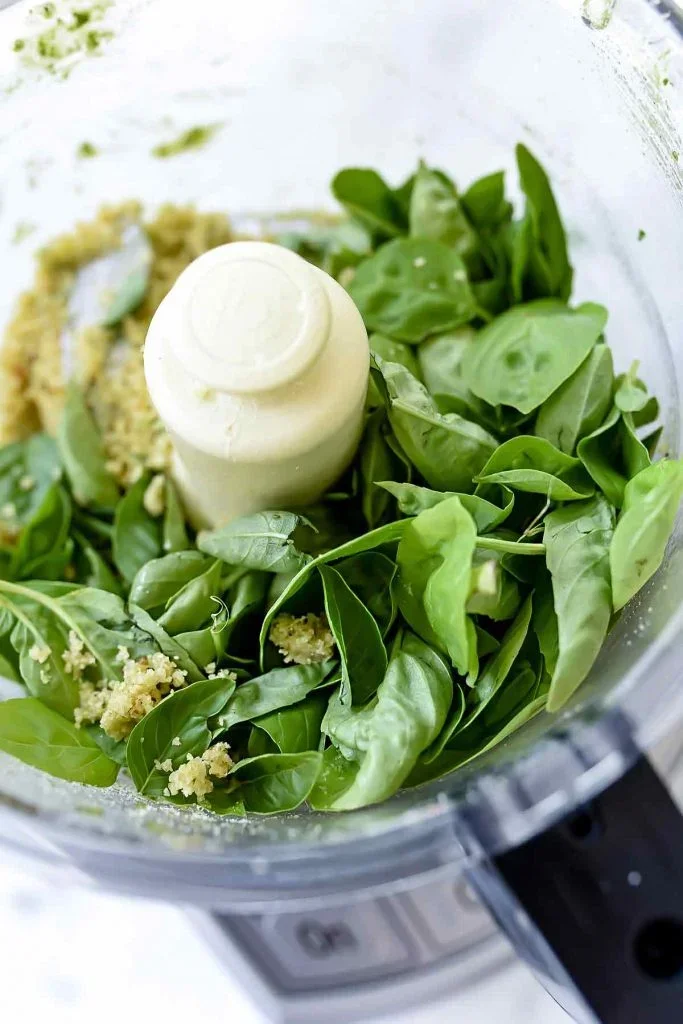 THE BEST Fresh Basil and Pine Nut Pesto - foodiecrush 3 fresh basil pesto ingredients arranged on wooden counter including pine nuts, parmesan cheese, and garlic