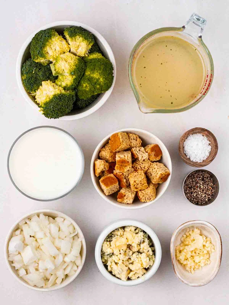 Ingredients for broccoli and stilton soup including broccoli, onion, and a block of stilton cheese