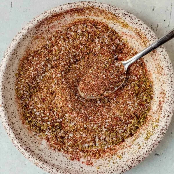 homemade carnitas seasoning blend in a small bowl with measuring spoons