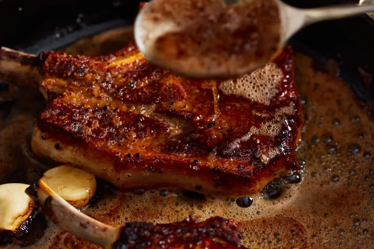 Cast Iron Pork Chops Recipe - The Cookie Rookie® 8 spooning brown butter over pork chops in cast iron skillet