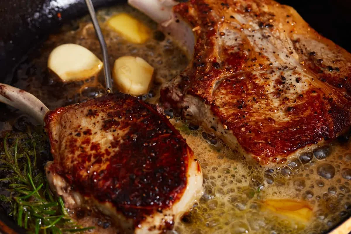 Cast Iron Pork Chops Recipe - The Cookie Rookie® 7 pork chops with melted butter, garlic, rosemary and thyme in skillet