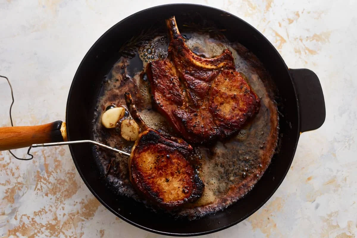 Cast Iron Pork Chops Recipe - The Cookie Rookie® 9 perfectly cooked pork chops resting on cutting board with juices
