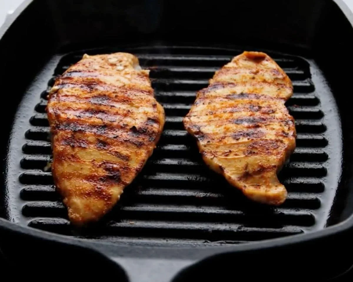 marinated chicken breasts cooking on a hot grill with sear marks
