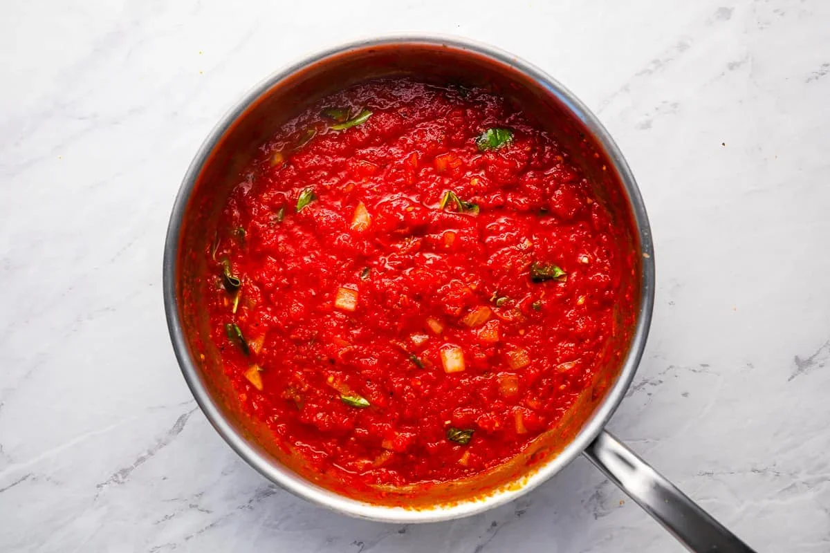 Homemade Spaghetti Sauce Recipe - The Cookie Rookie® 5 fresh basil being stirred into finished spaghetti sauce
