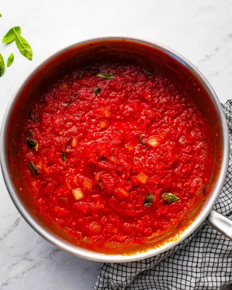 homemade spaghetti sauce simmering in stainless steel pot with fresh basil