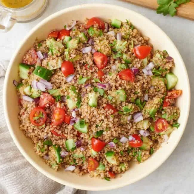 fresh quinoa avocado salad in a white bowl with lime wedges