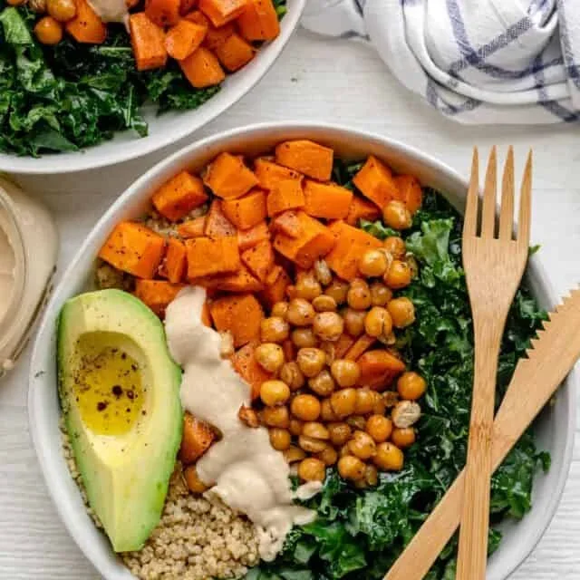 finished vegan quinoa buddha bowl with avocado, sweet potatoes, and tahini dressing