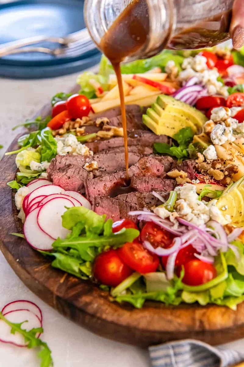 finished steak salad drizzled with balsamic vinaigrette dressing