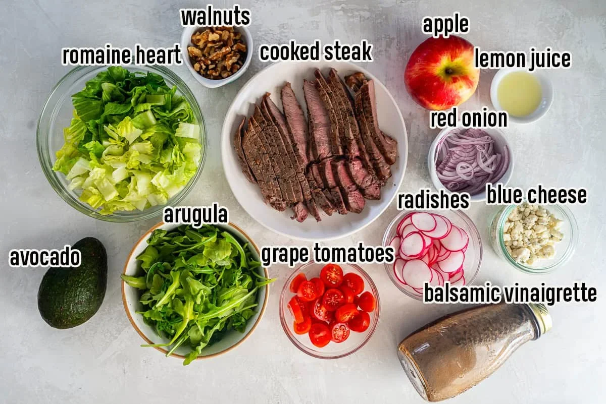 ingredients for steak salad including sirloin, romaine, arugula, apples, and walnuts