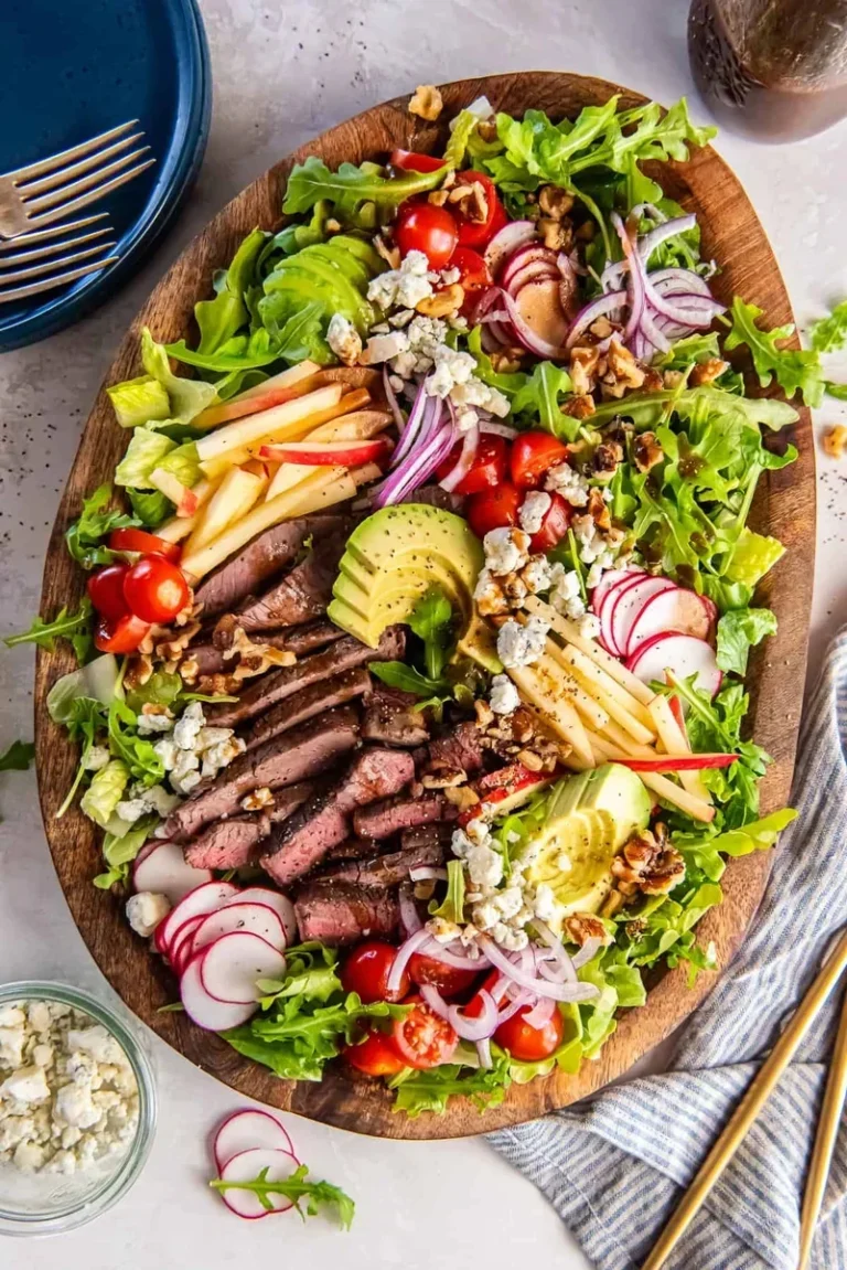perfectly cooked sliced steak arranged on top of salad greens