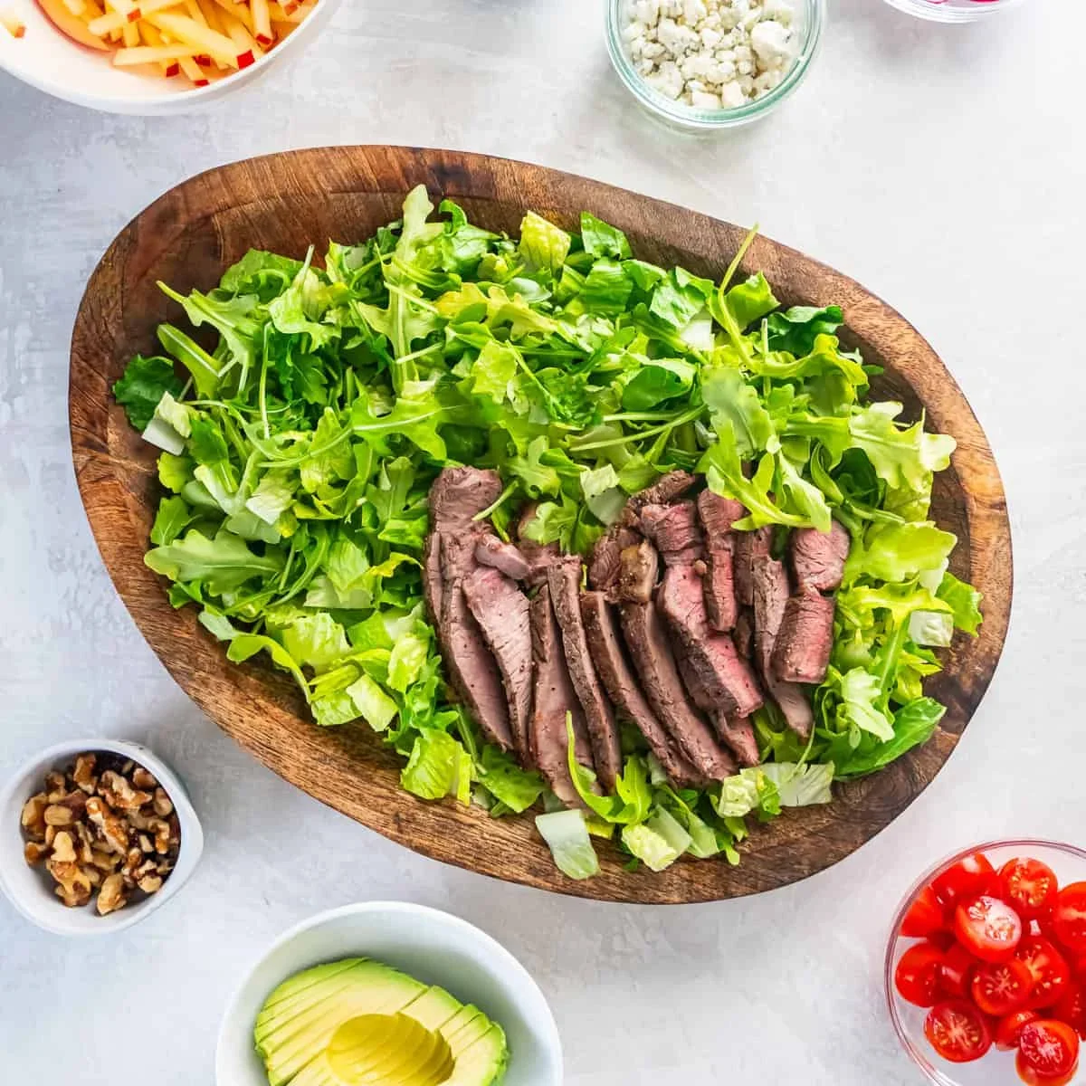 perfectly cooked sliced steak arranged on top of salad greens
