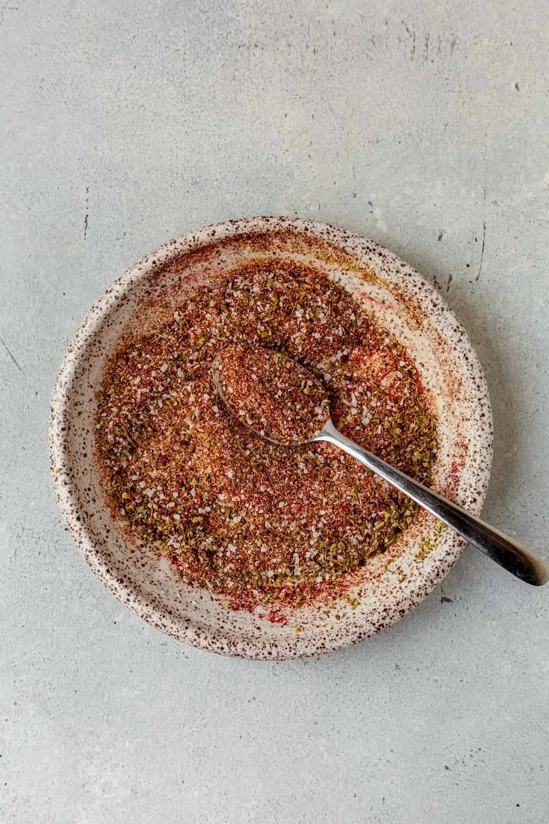 wooden spoon blending homemade carnitas spices in a bowl