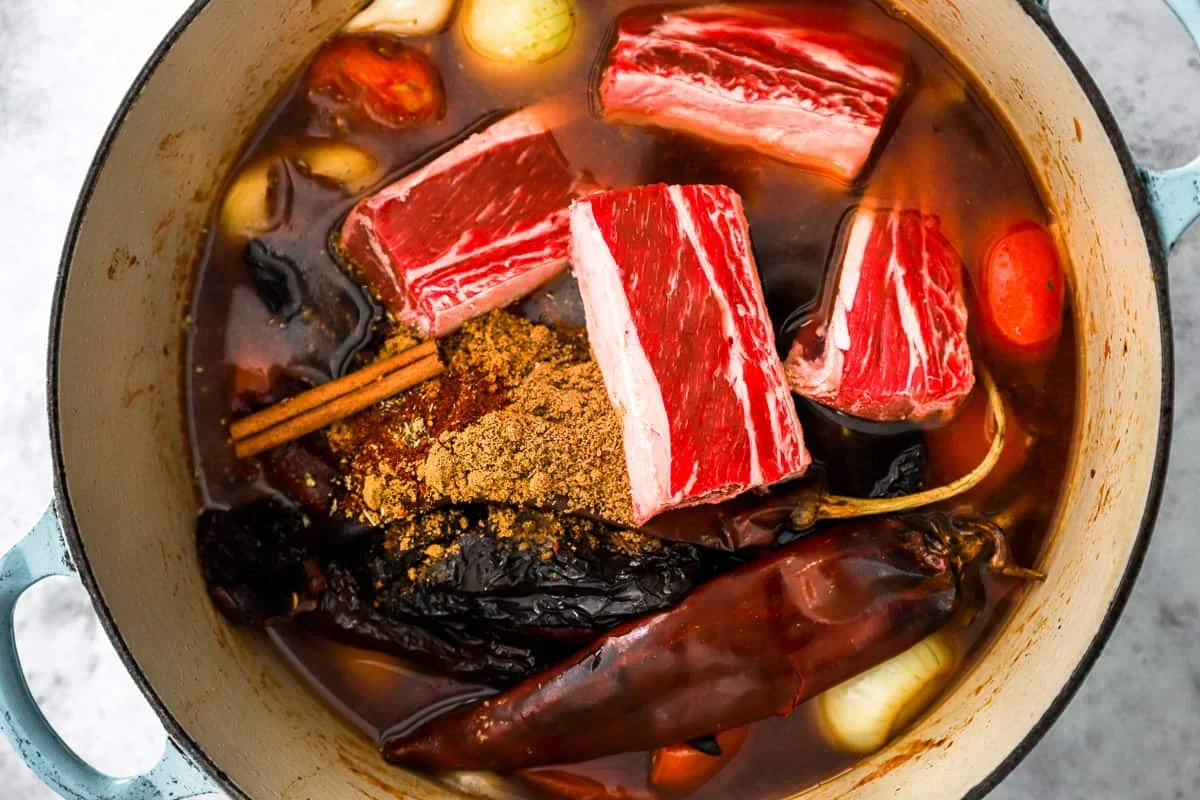 deglazing a dutch oven with beef broth for birria tacos sauce