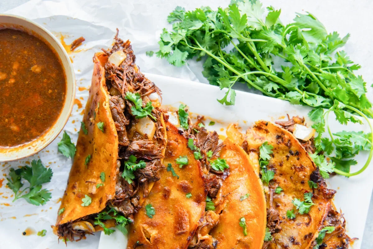 frying a folded birria taco until crispy and golden brown in a skillet