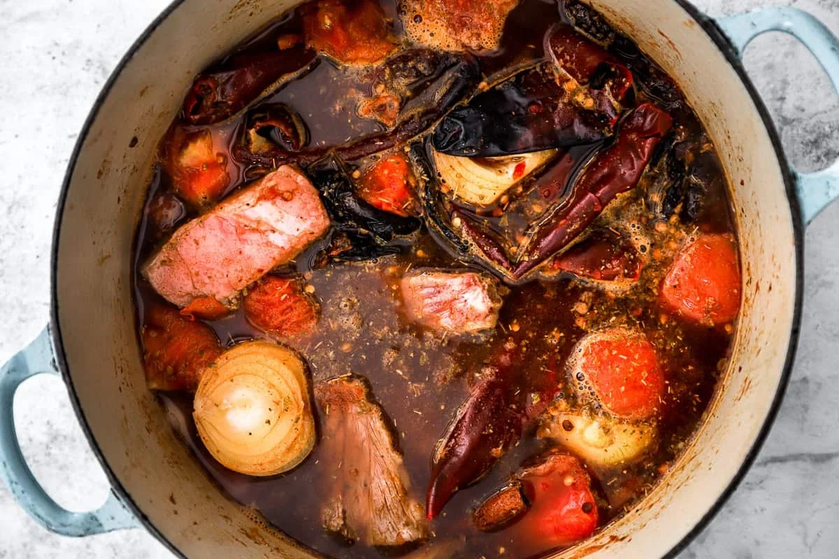 simmering birria broth with short ribs and spices in a dutch oven