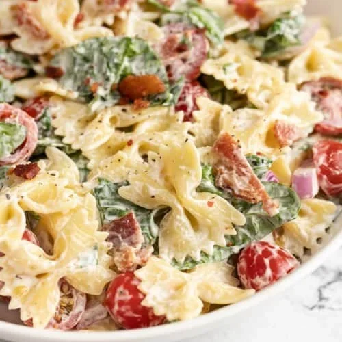 Close up of cold pasta salad with crispy bacon and fresh spinach