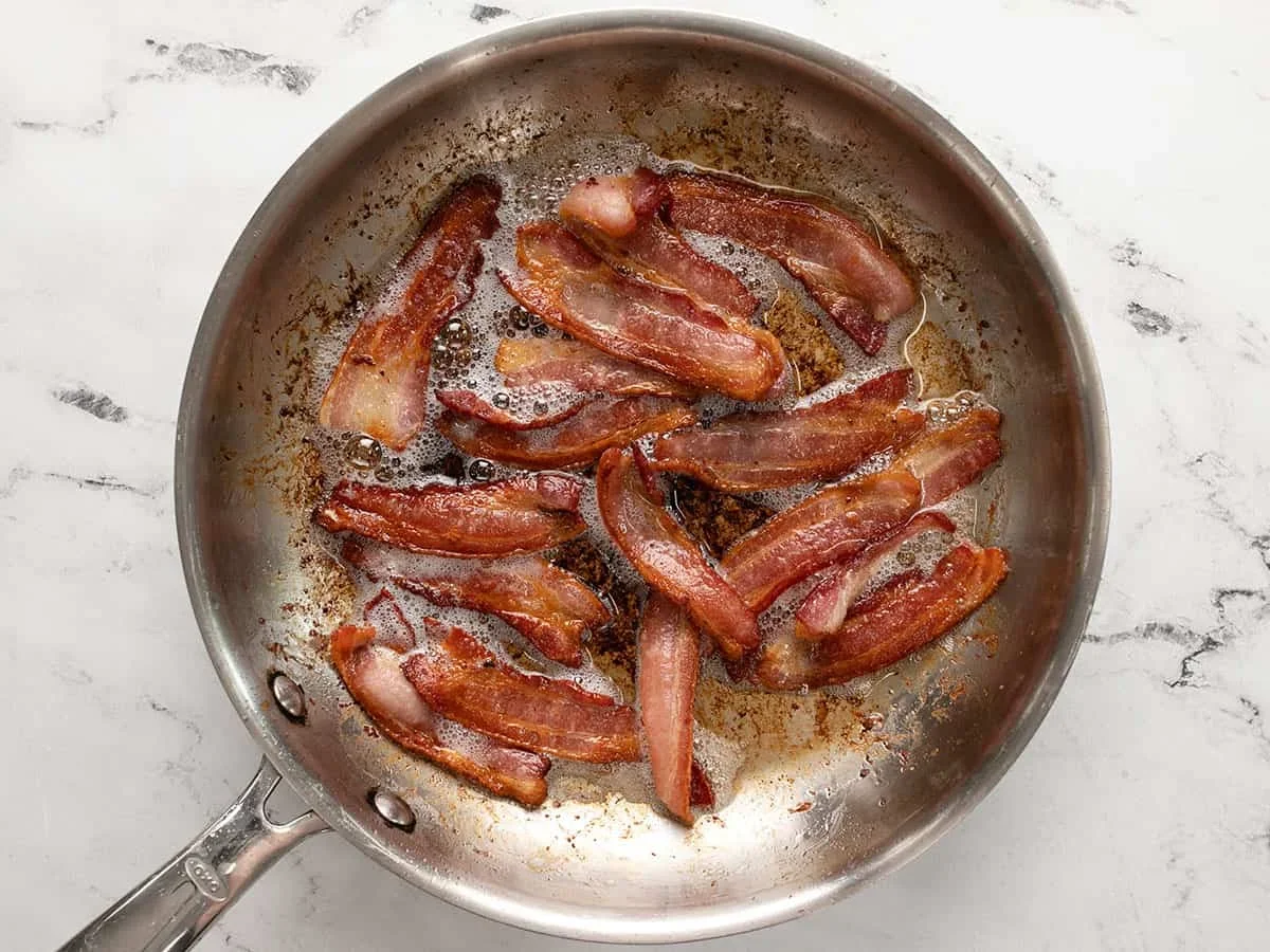 crispy bacon cooking in a skillet for blt pasta salad