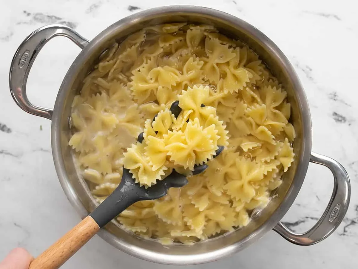 cooked bowtie pasta draining in a metal colander