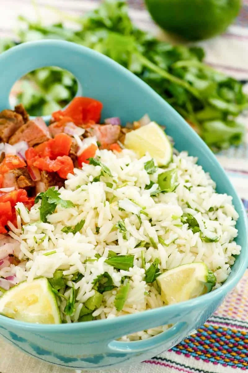 fluffy cilantro lime rice in a bowl with fresh lime wedges