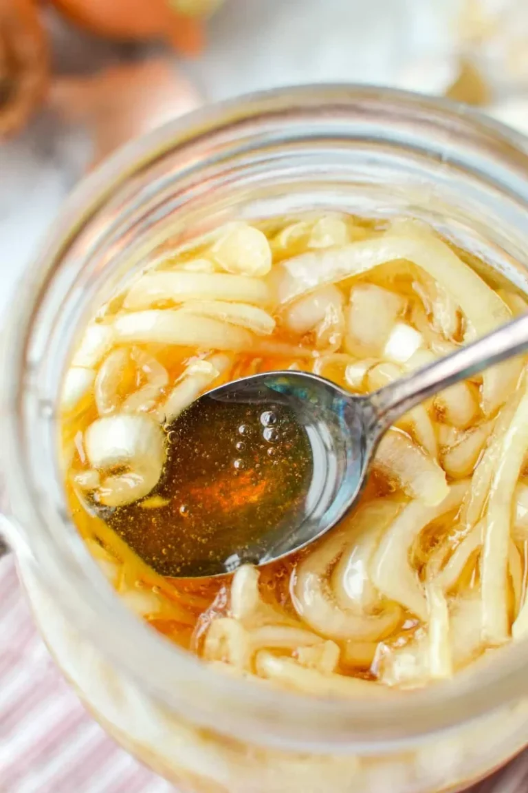 jar of homemade honey onion cough syrup with sliced onions and garlic