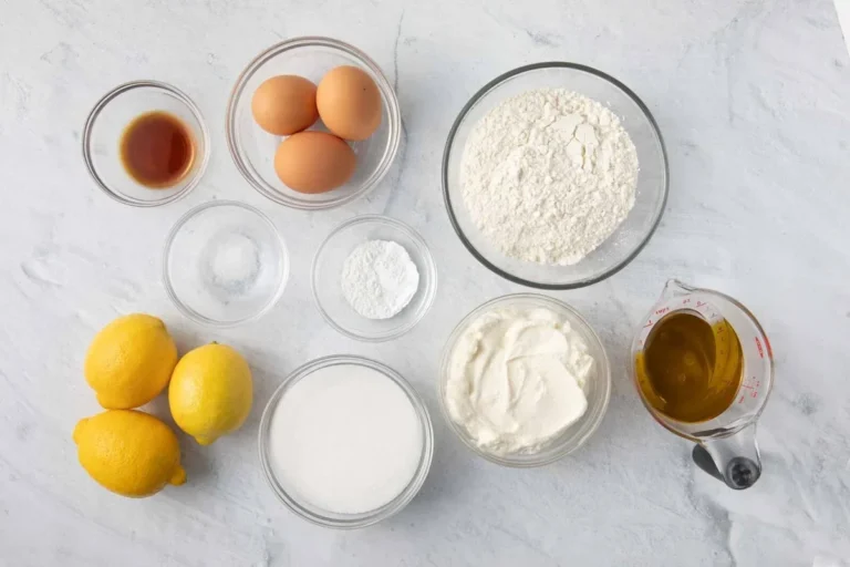 ingredients for lemon ricotta cake including lemons, ricotta, and olive oil in a mixing bowl