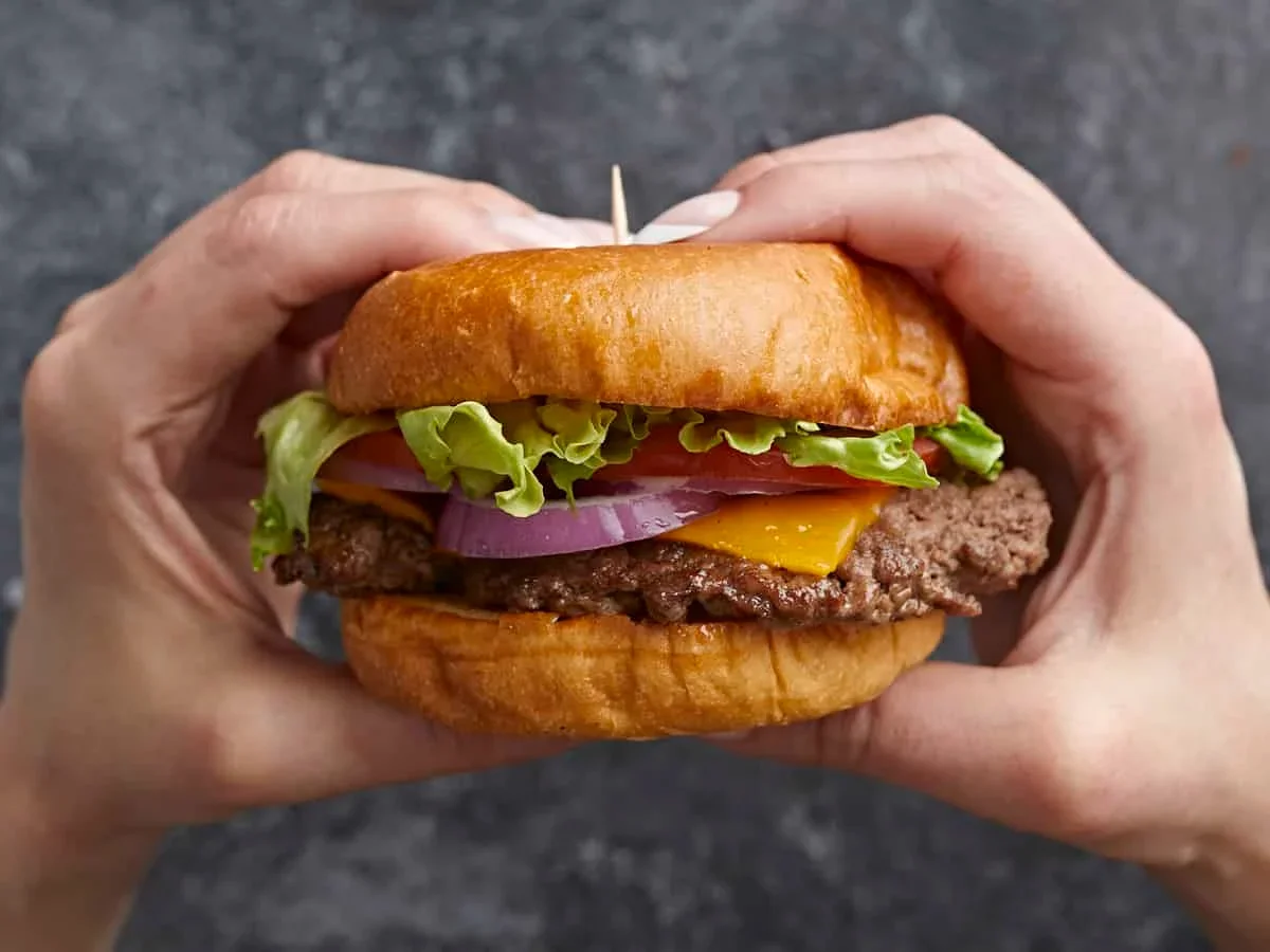 Easy Smash Burger Recipe with Crispy Edges in 30 Minutes 3 pressing smash burger with heavy spatula on cast iron skillet