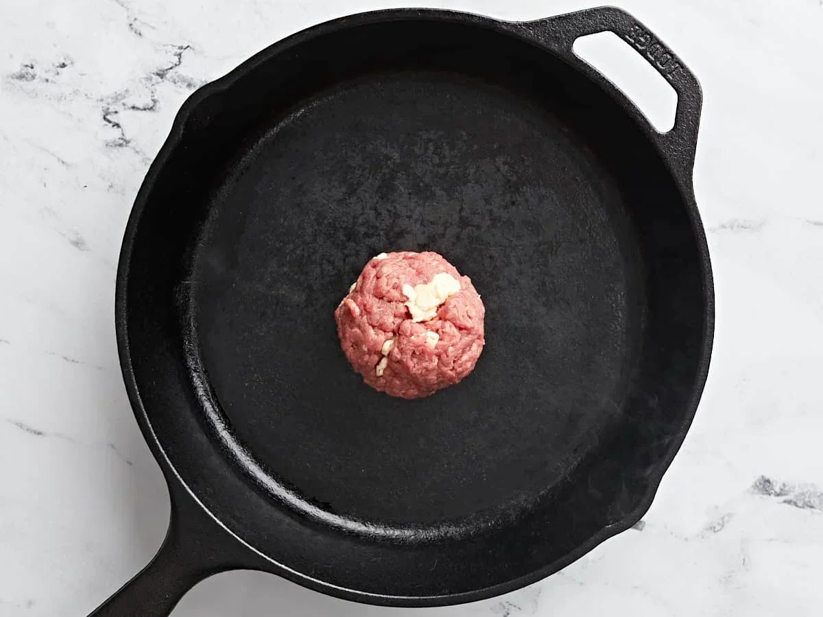 Easy Smash Burger Recipe with Crispy Edges in 30 Minutes 6 seasoned beef ball placed in hot cast iron skillet for smash burgers