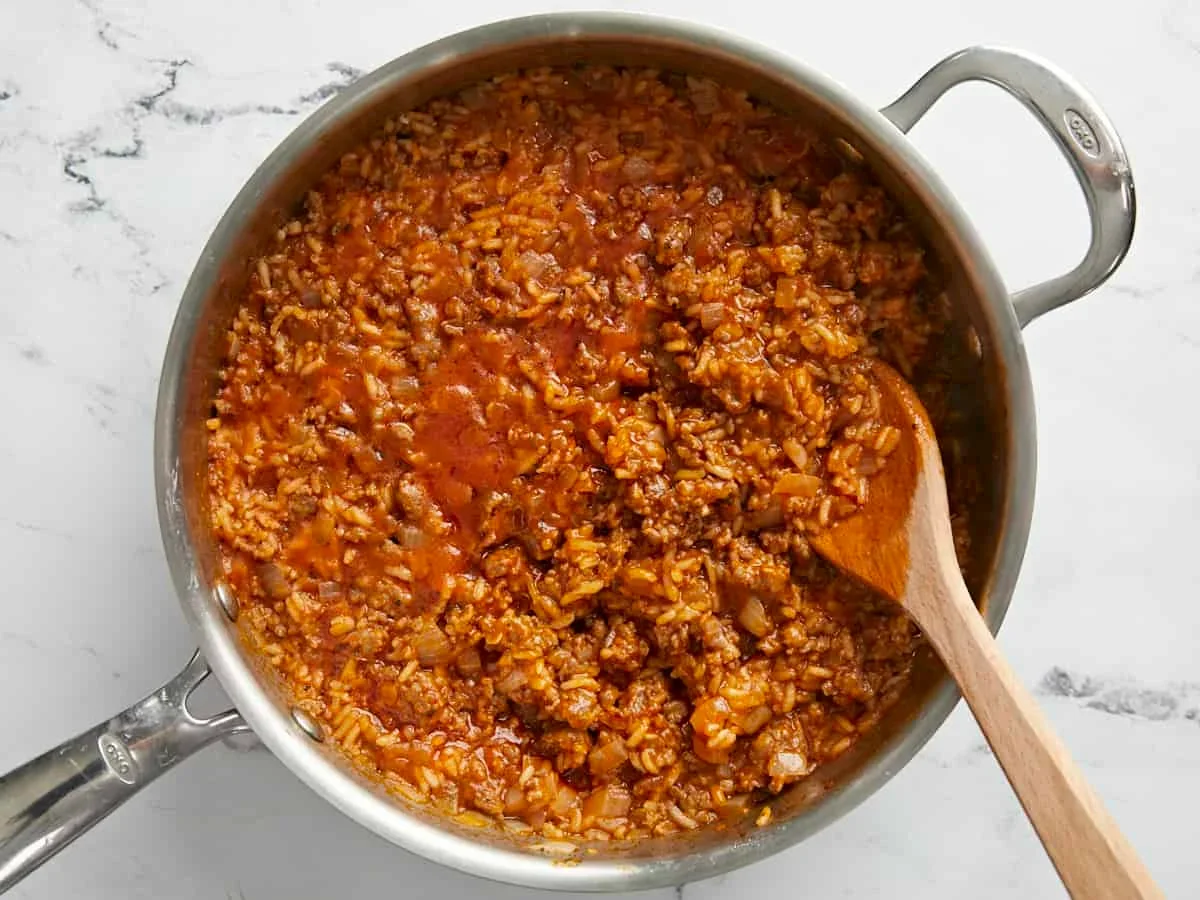 raw stuffed bell peppers filled with sausage and rice mixture in a baking dish