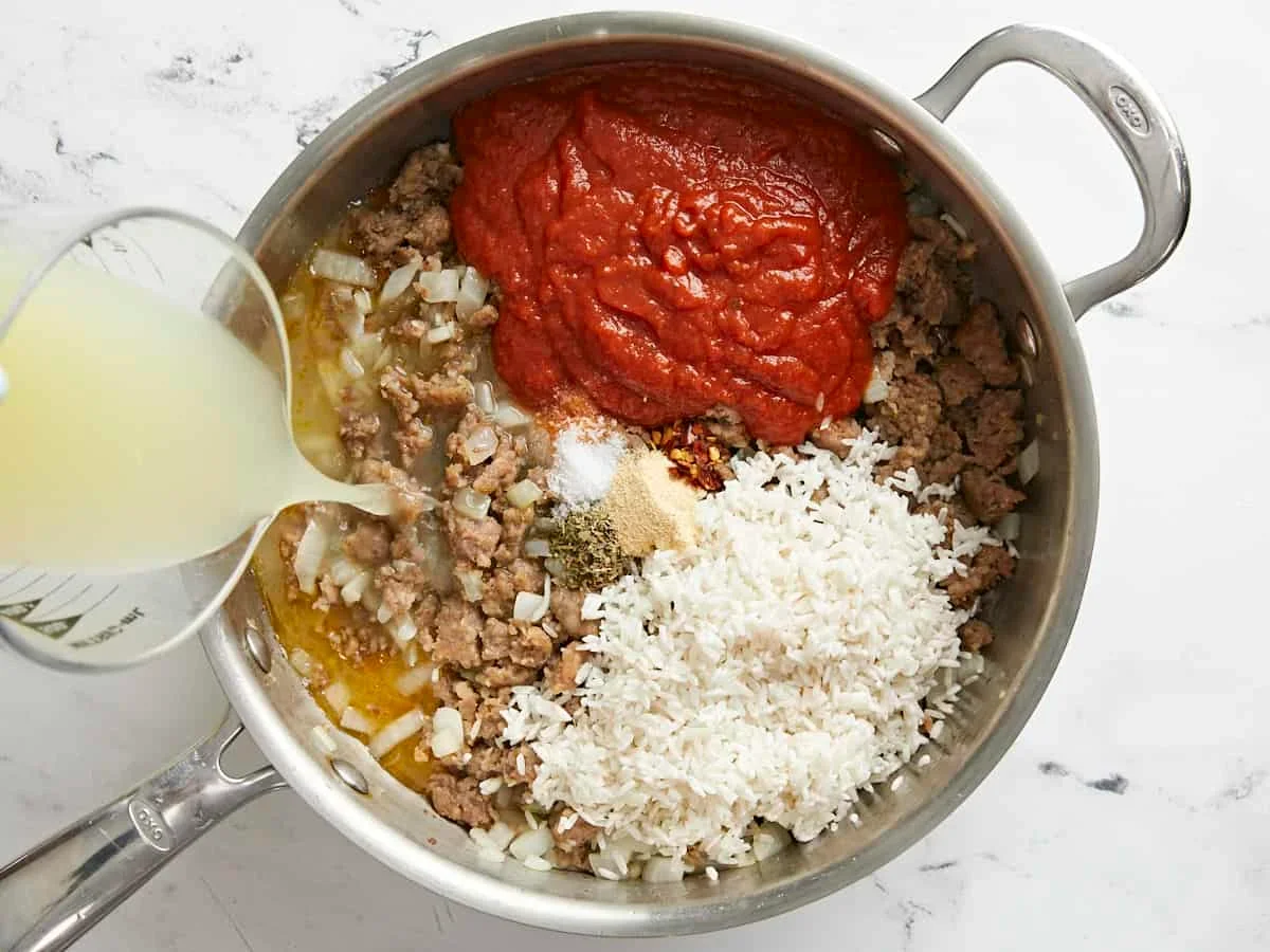 skillet with rice and marinara sauce simmering for stuffed bell peppers filling