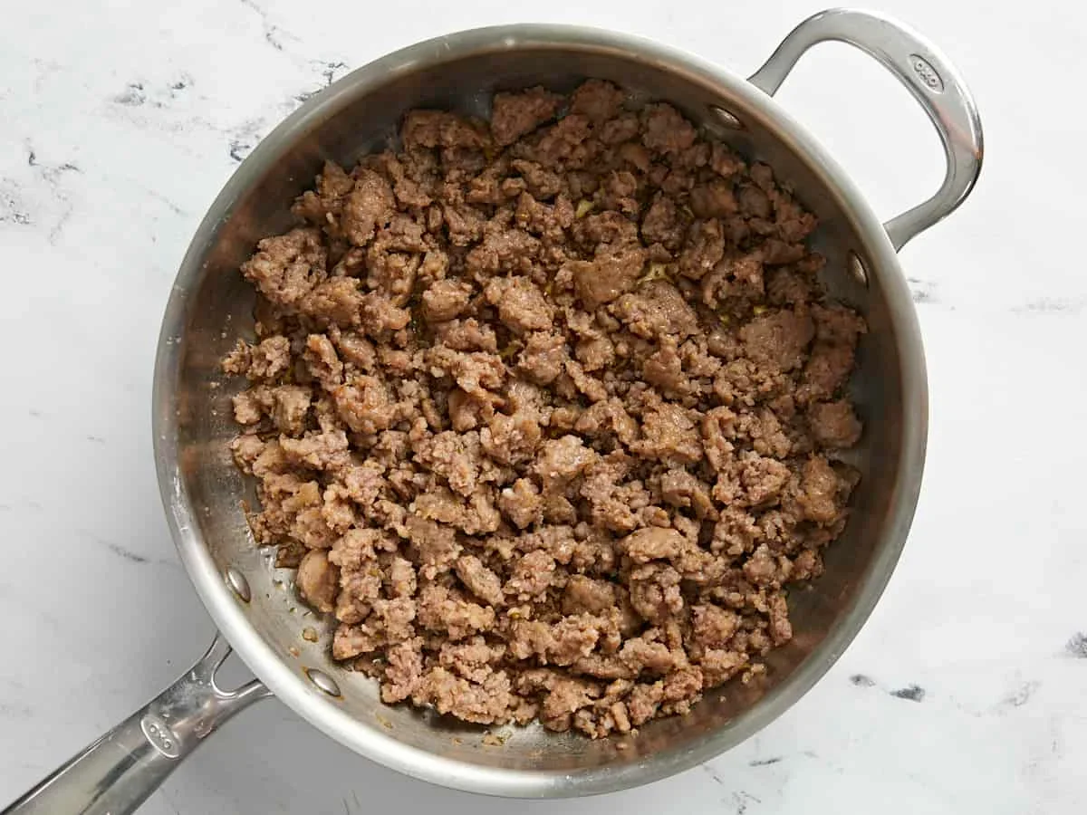 crumbled Italian sausage browning in a skillet for stuffed bell peppers